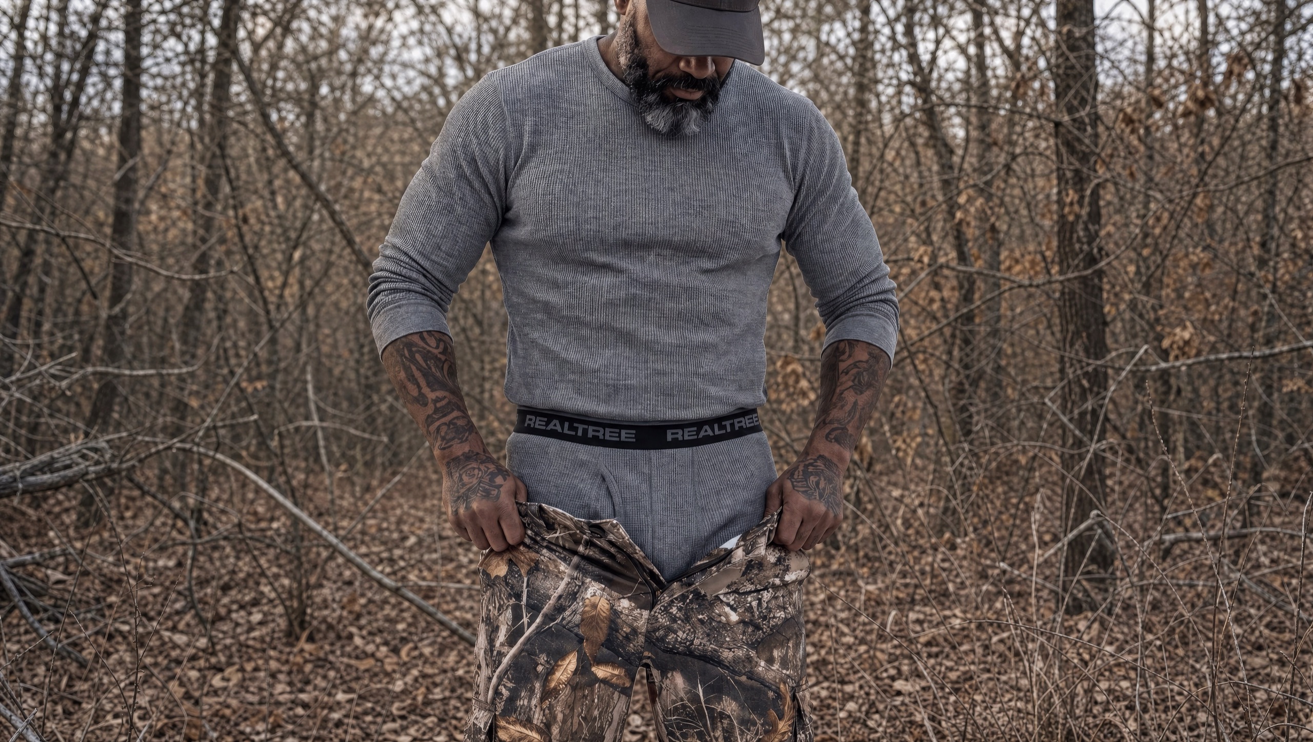 Hunter in a Realtree thermal base layer among bare winter trees