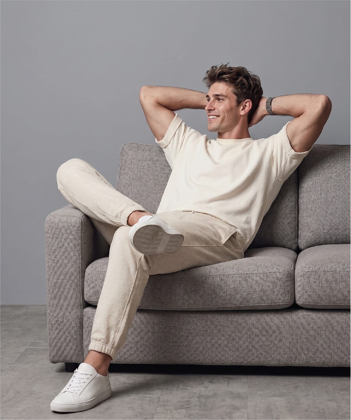 Man reclining on a sofa in a relaxed cream tee and joggers